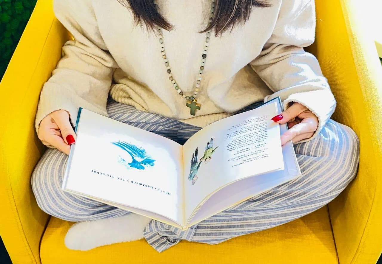 Раскрытая книга в руках: разворот с текстом и иллюстрацией
